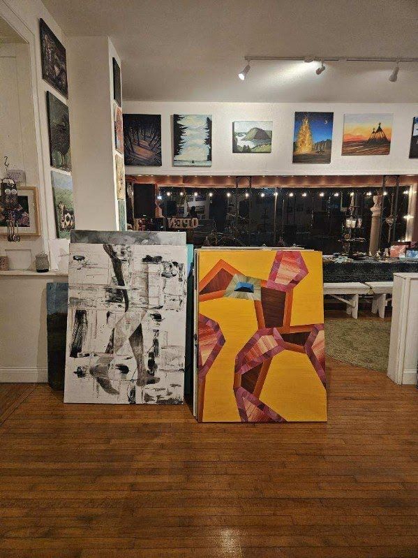 View across the gallery floor with paintings leaning against the wall and hanging in the back room