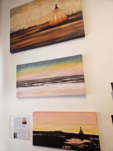 Sunset and shoreline paintings on the gallery wall